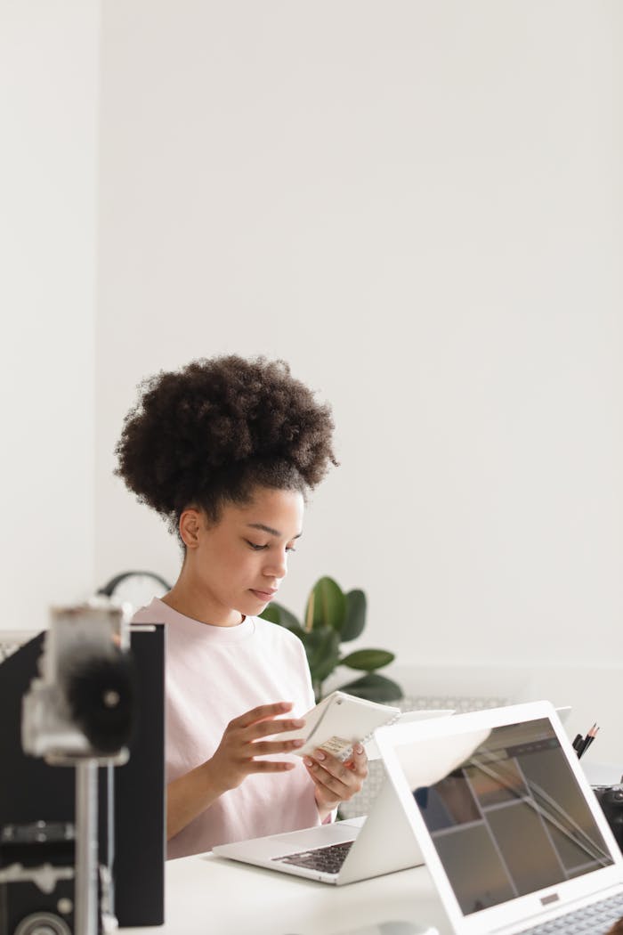 Young woman using a laptop and smartphone in a modern office setting, focused and engaged.